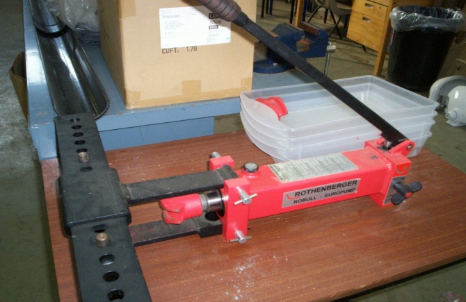 A hydraulic bender set up on a bench