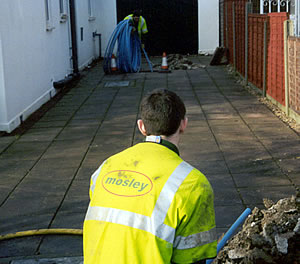 An operative jetting a drain outside a property