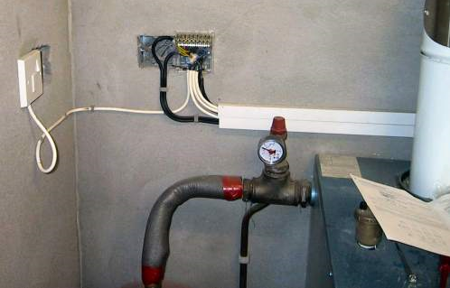 A sealed system pressure gauge and filling loop beside a cylinder