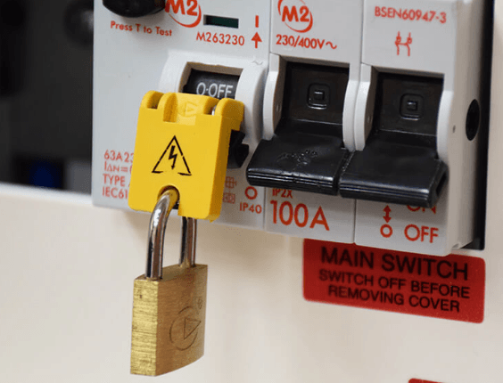 A lock-off device with a brass padlock securing a circuit breaker in the off position, preventing it from being switched back on while work is carried out