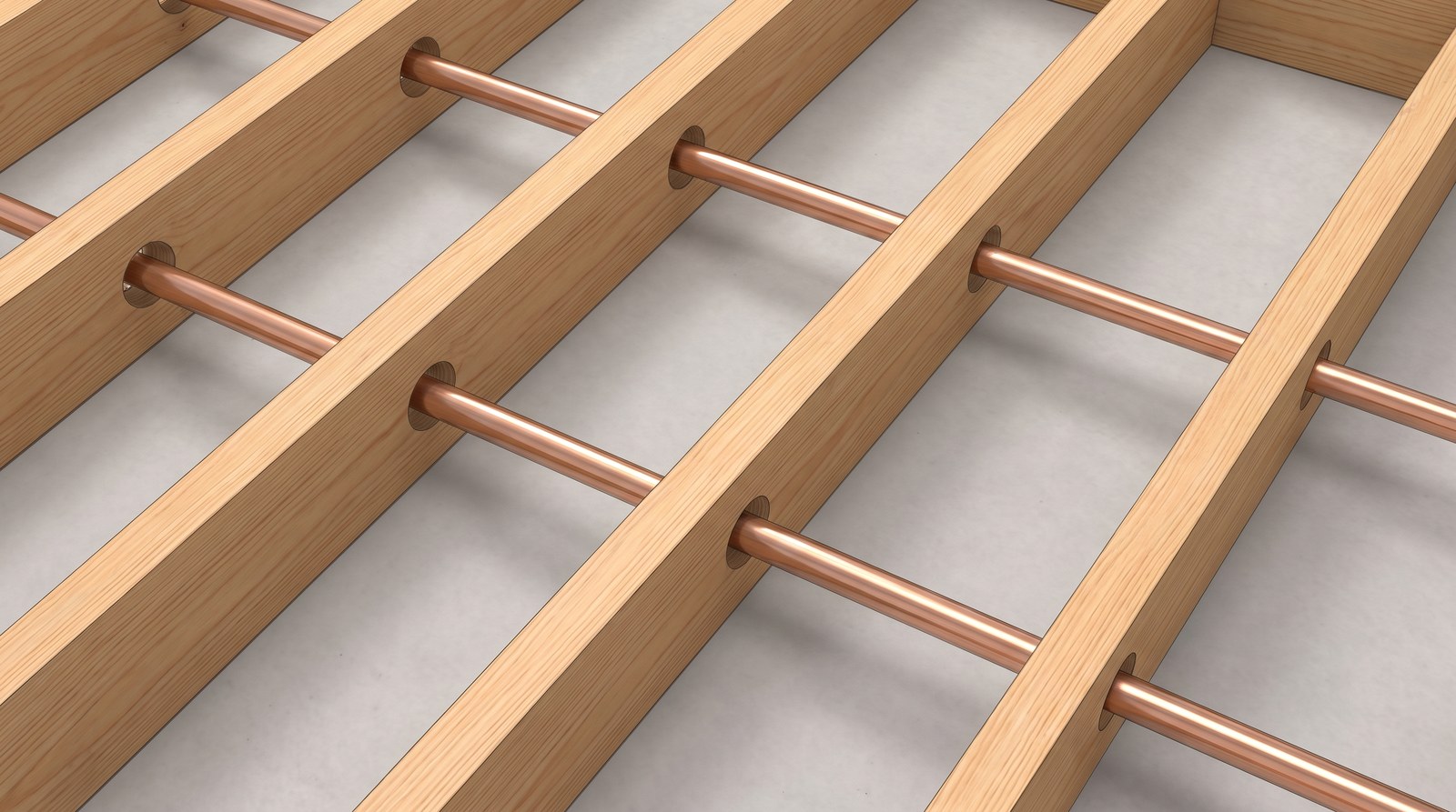 Timber floor joists seen from above with copper pipes passing through neat holes drilled on the centre line of each joist